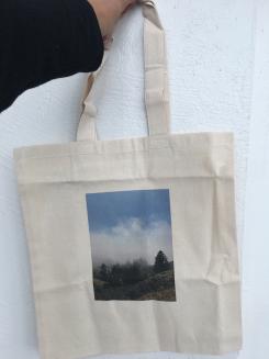 Tote bag with a picture of some mountains and trees on it.