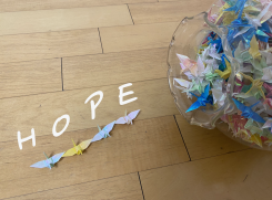 Colorful origami paper cranes with the word hope laid on the ground.