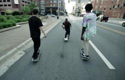 Boys skateboarding down a street