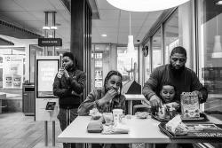 Roland Whitley sits with his son and two mentees at a McDonalds in a photo that was part of a series that won the 2019 Dorothea Lange Fellowship