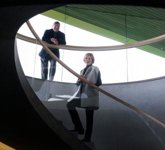 The Kramlichs, known as Pam and Dick, on a monumental staircase that connects the underground galleries and a mezzanine to the glass pavilion.