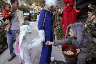 Miles Miesnieks, 7, gets a handful of candy with his mom, Silka, from Marie Van Wassenhoven (right) as they trick-or-treat on 24th Street in Noe Valley as San Francisco celebrated Halloween in 2016.