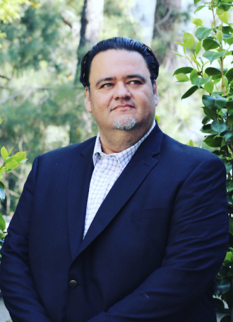 Pablo Gonzalez, wearing a navy blazer and white dress shirt, poses for a portrait.