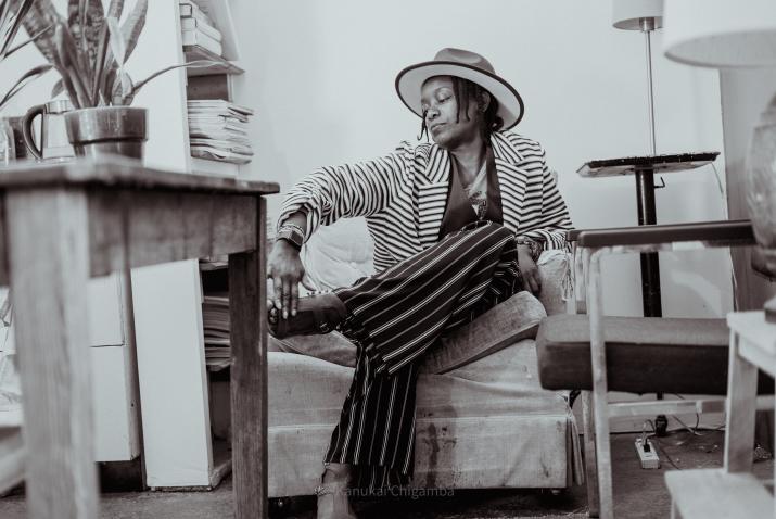 In a black and white image, Latanya Tigner sits on a couch. 