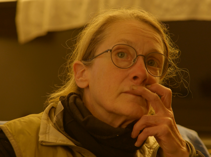 close up of a women with glasses, fingers resting above her lips in a pensive manner