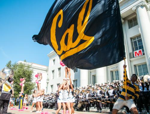 Student waving Cal flag in front of the Cal Band at Sproul Hall. 