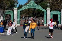 Students in masks walking through Sather Gate.