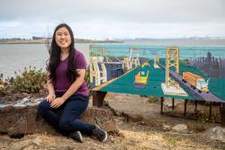 UC Berkeley student Heidi Dong sitting next to the art installation she co-created at the Albany Bulb.